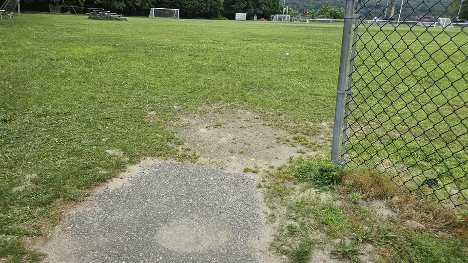 The end of the paved path that leads into the soccer field.
