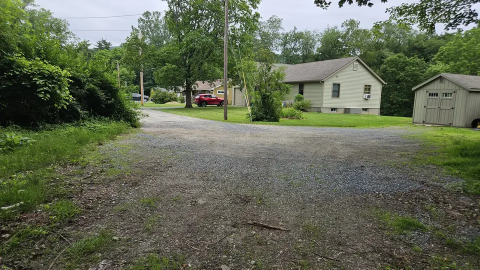 The grassy and gravel parking area.