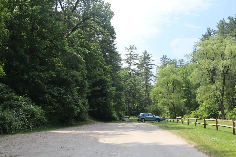 Gravel parking area for Umpachene Falls, featuring a portable restroom and parking for at least 15 cars.
