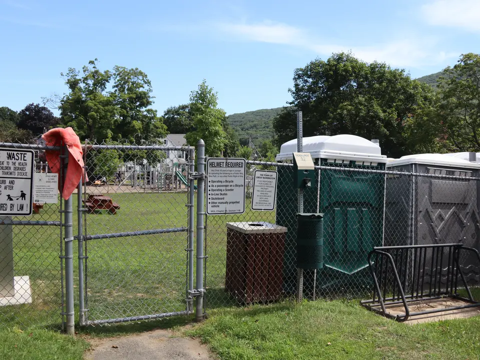 Entrance to the playground, which can be accessed through a metal gate. Portable restrooms are also located next to the entrance.