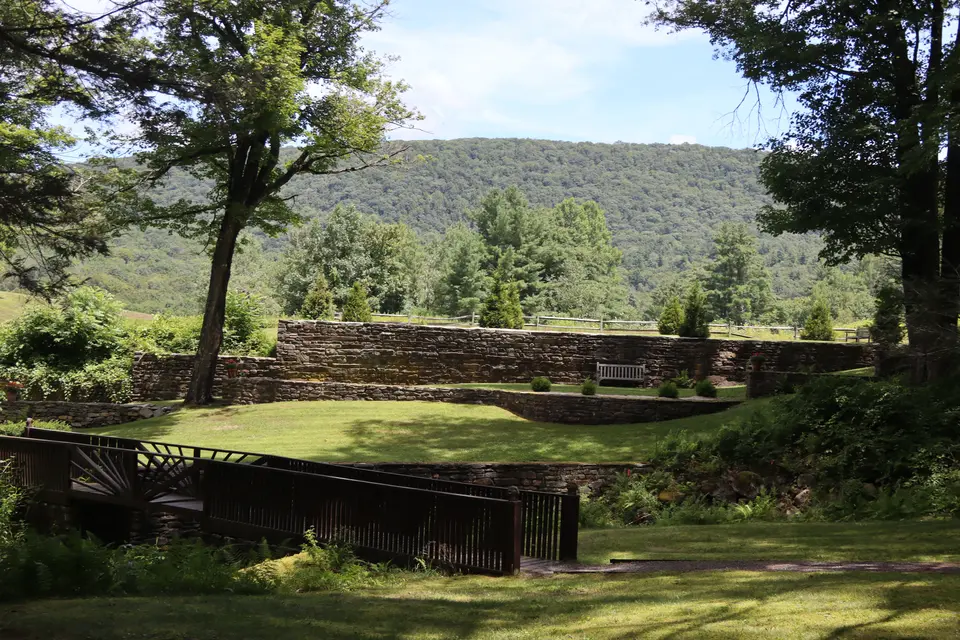 View of the Gardens, included a wooden bridge, and wooden picnic benches along a stone wall.