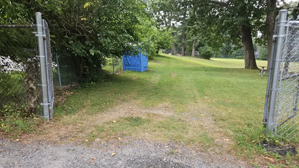 A grass slope leading down into the park from the parking lot.