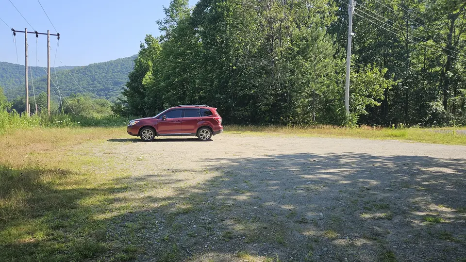 A car in the flat and even gravel parking lot, near the trailhead.