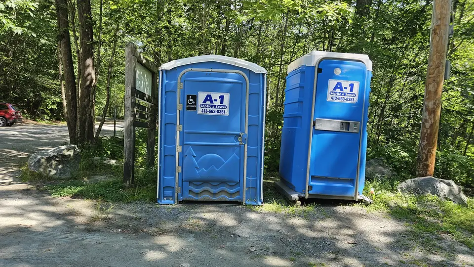 An accessible port a potty and a non-accessible port a potty, near the parking lot.