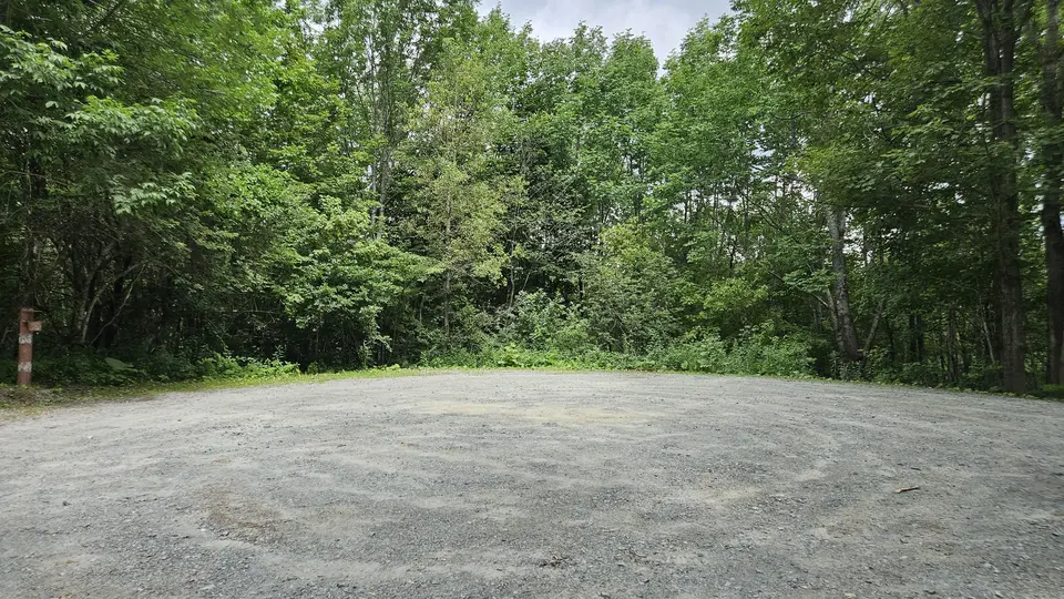 The large, flat gravel parking lot with loose gravel.