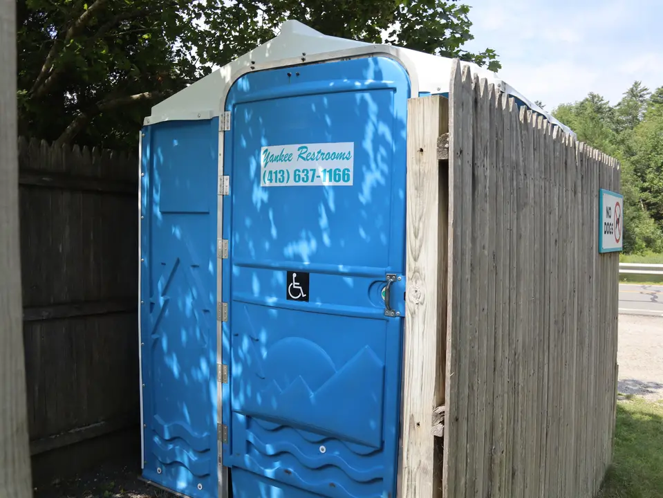 An accessible portable restroom located between the parking area and beach.
