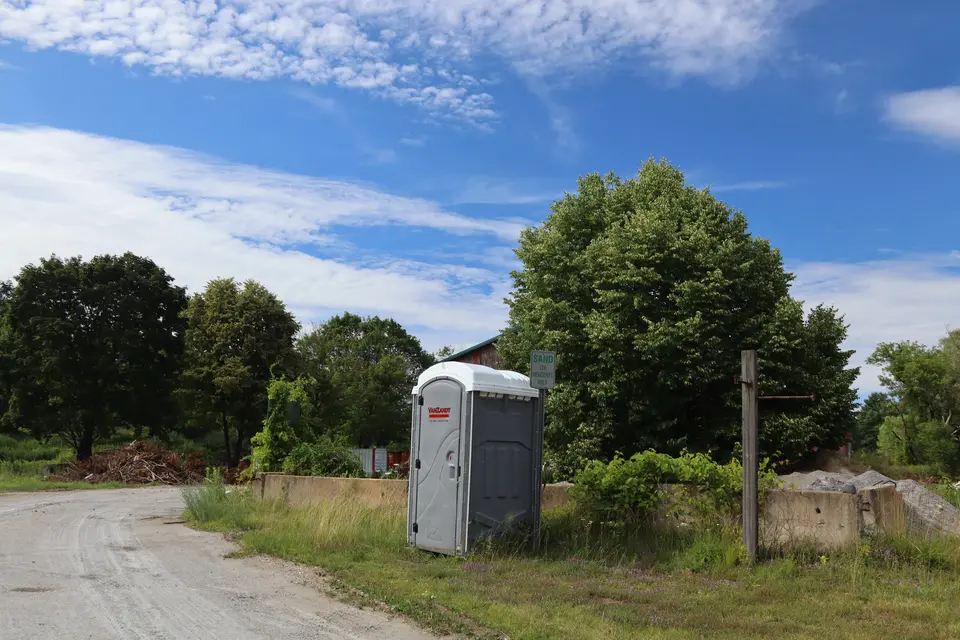 A portable restroom sits across from the Lee Soccer Fields, close to the parking area. 