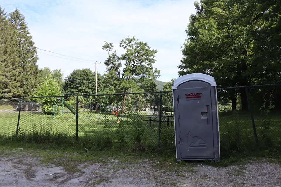A portable restroom sits adjacent to the Marble Street Playground and parking lot.