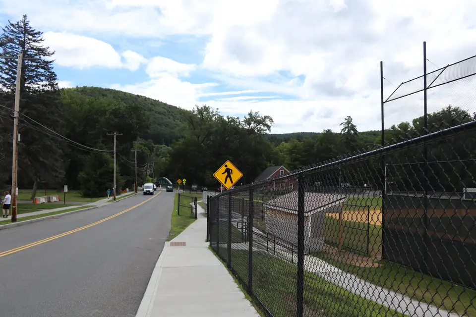Sidewalk access to memorial park, which leads down a gently sloped hill.