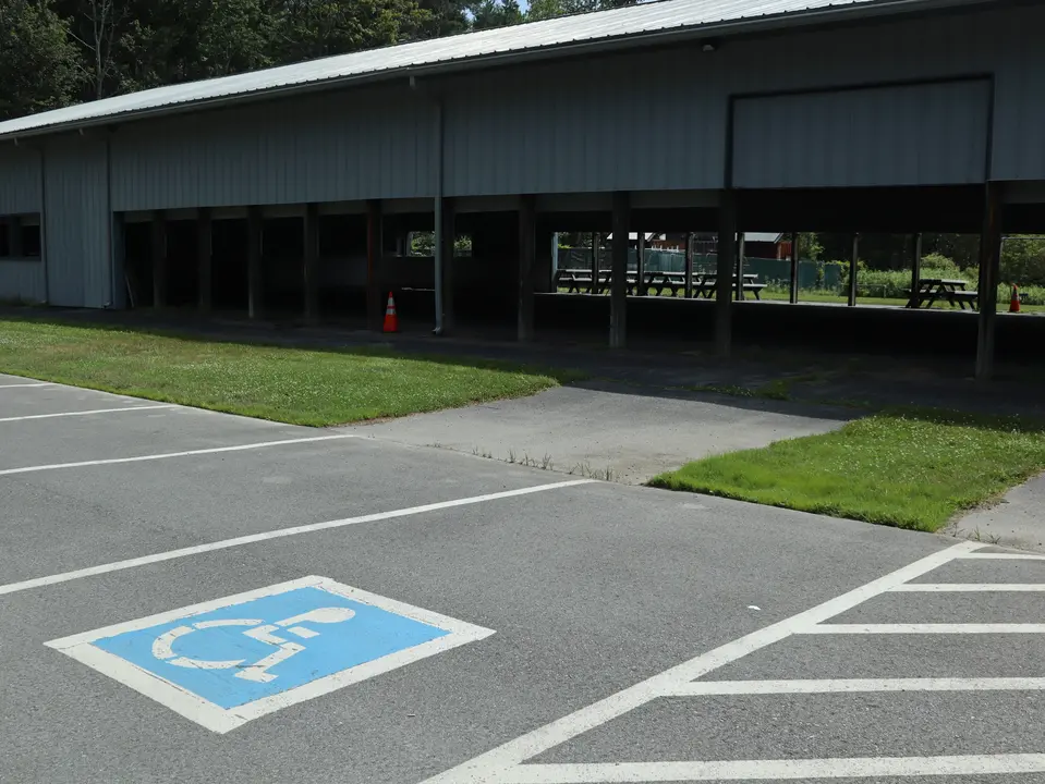 An accessible parking space located adjacent to a paved path that leads into the rink building.
