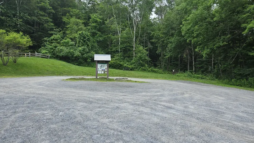 A large gravel parking lot with an information sign.