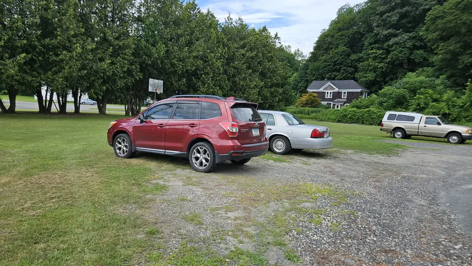 A small parking area, made of both grass and gravel.