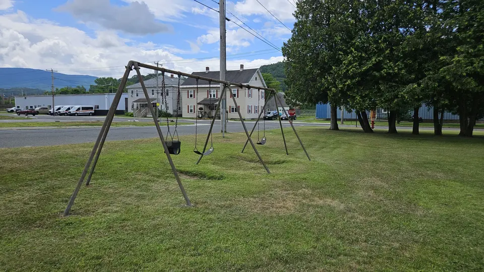 A swingset, with flat grass surrounding it.