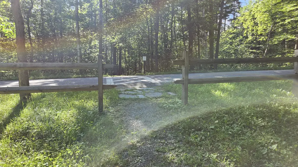 The gap in the fence by the parking lot, going to the trailhead.