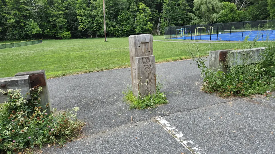 A gap in the fence from the parking lot to the paved path.