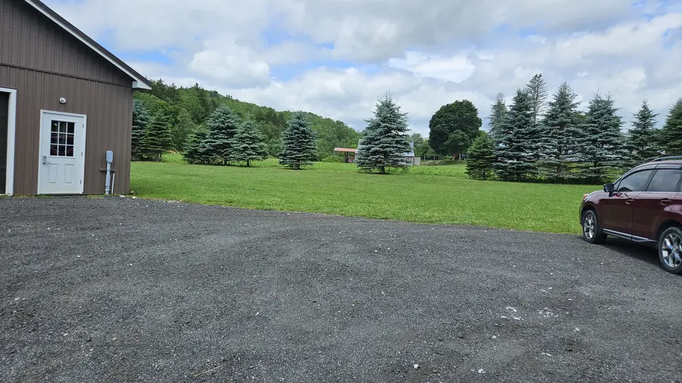 The gravel parking lot, with grass field behind it.
