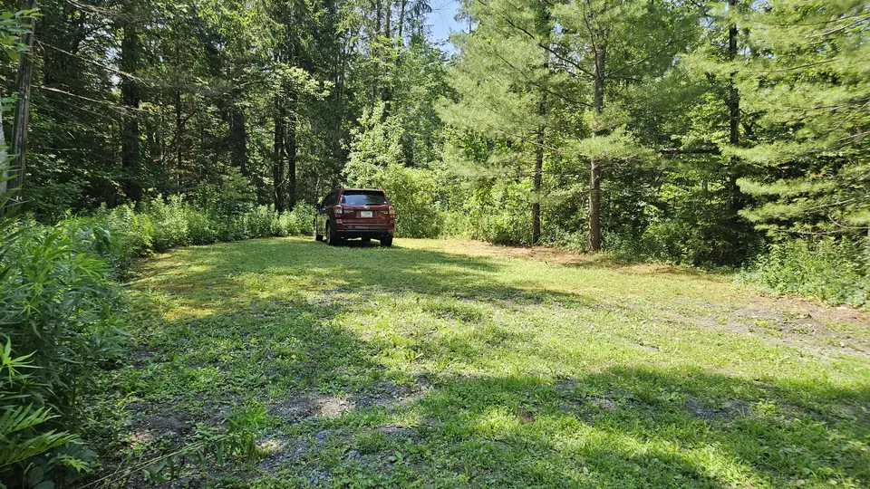 The uneven grass parking lot, behind the even and flat gravel parking lot.