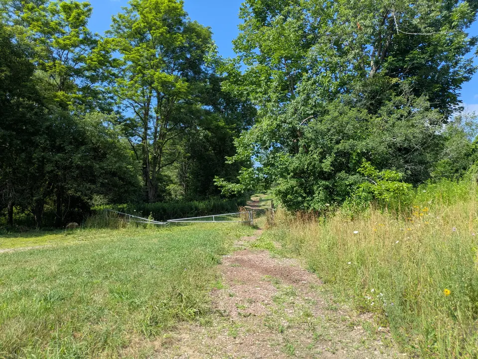 Trail running past parking area through a gate