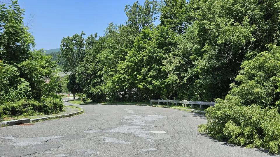 The entrance to the parking lot; a paved road.