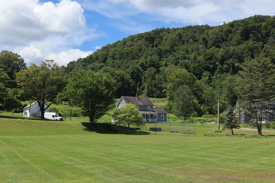 An open grassy field in Tyringham Town Park, which is slightly sloped to the northeast.