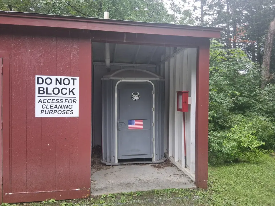 Portable restroom located on the south side of the parking area.