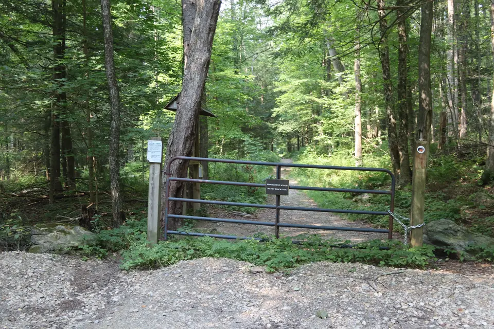 Entrance to Old Baldhead Road from the parking lot, through a narrow gap next to a metal gate.