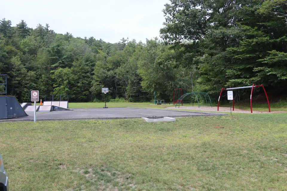 A slight grassy slope runs up to the playground from the parking area.